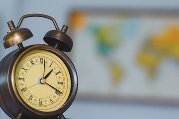 Alarm clock on hand with retro world map background.