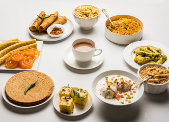 Group of Gujarati snacks like jalebi-fafda, thepla, khaman dhokla, aloo bhujiya, khandvi,khakra, dahi vada, gathiya with hot tea