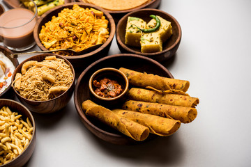 Group of Gujarati snacks like jalebi-fafda, thepla, khaman dhokla, aloo bhujiya, khandvi,khakra, dahi vada, gathiya with hot tea