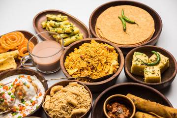 Group of Gujarati snacks like jalebi-fafda, thepla, khaman dhokla, aloo bhujiya, khandvi,khakra, dahi vada, gathiya with hot tea