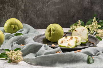 Tasty pears with nuts. A table decorated with flowers and a plate of pears cut into the plate