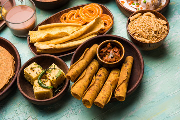 Group of Gujarati snacks like jalebi-fafda, thepla, khaman dhokla, aloo bhujiya, khandvi,khakra, dahi vada, gathiya with hot tea