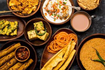 Group of Gujarati snacks like jalebi-fafda, thepla, khaman dhokla, aloo bhujiya, khandvi,khakra, dahi vada, gathiya with hot tea