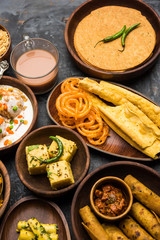 Group of Gujarati snacks like jalebi-fafda, thepla, khaman dhokla, aloo bhujiya, khandvi,khakra, dahi vada, gathiya with hot tea