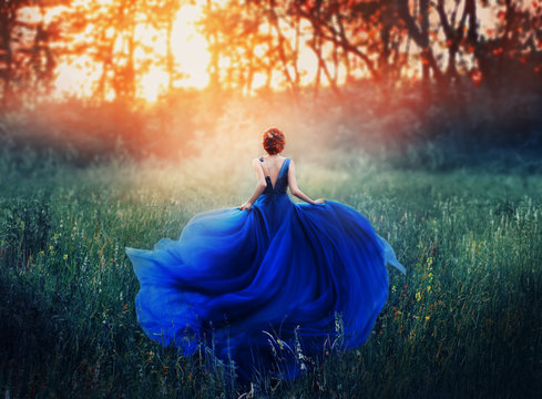 princess, with a elegant hairstyle, runs through a forest meadow to meet a fiery sunset with a haze. A luxurious blue dress with a long train flutters in the wind. Photo from the back without a face.