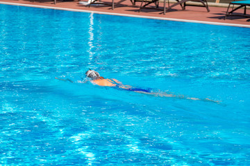 Woman with swimsuit swimming on a blue water pool.