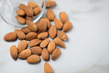 Ungeschälte braune Mandeln in Glas Schale auf Marmor Hintergrund