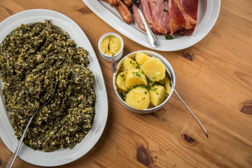 Oldenburger Grünkohl, Kassler Nacken, Kohlwurst und Pinkel auf Platten mit Kartoffeln und Senf auf Holz Tisch