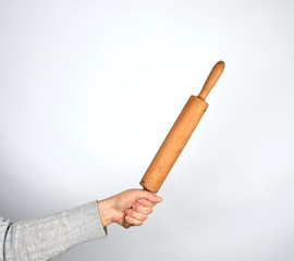 hand holding a wooden rolling pin on a gray background