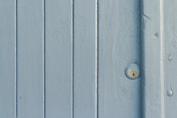Wooden door painted in light blue with a small lock