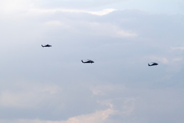 Military helicopters on blue sky with clouds and birds.
