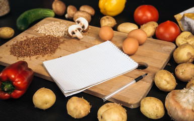 Shopping list, recipe book, diet plan. Fresh raw vegetables, fruit and ingredients for cooking. top view, place for text. Diet or vegan food, healthily cooking concept. Flat lay. Notepad for your reci