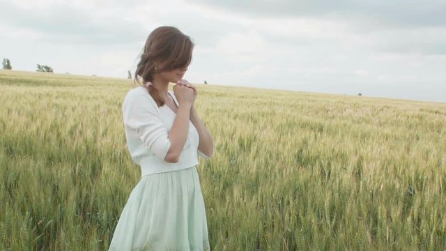 a young girl praying in a wheat field, a woman among ears of corn enjoying nature and thanking God, a concept of religion and faith