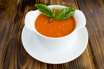 Tomato soup in the white bowl on the brown  wooden background.Closeup.
