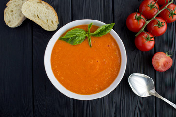 Tomato soup in the white  bowl on the  black wooden background.Top view.Copy space.