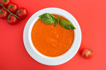 Tomato soup in the white  bowl on red background.Top view.Closeup.