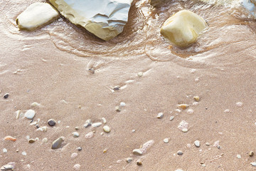 Fototapeta na wymiar Sand pebbles beach and the waves on sea at sunset or dawn