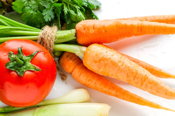 Fresh carrot with green leaves, tomato, onion and parsley on white background.