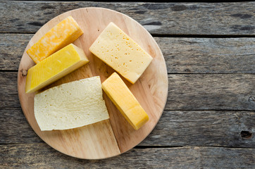 Wide variety of cheese on an old, rustic wooden table.