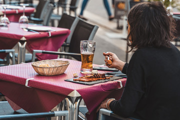 Woman eating octopus and drinking beer at the terrace. Spanish seafood, food tourism.