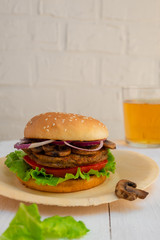 Homemade mushroom veggie burger on white wooden background with copy space.