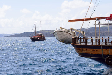 White rescue boat on the bow of a wooden pleasure boat in the old port of the Greek city of Fira. Beautiful view of the mountains, the sea and the ships, Santorini Island, Greece.