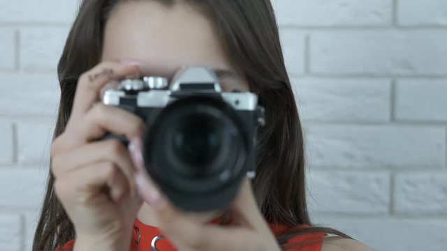 Young photographer. Charming young girl with a camera with the inscription SMILE on her hand.
