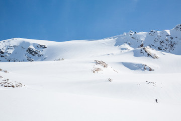 Fototapeta na wymiar Youngs Peak above backcountry skier skinning uphill toward the Seven Steps of Paradise ski line.