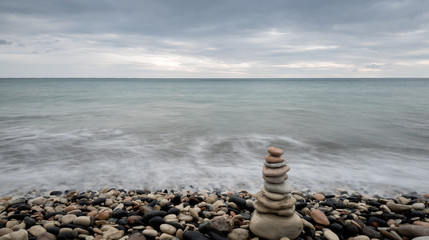 Fototapeta na wymiar Pyramid of balancing stones , in the wavy ocean