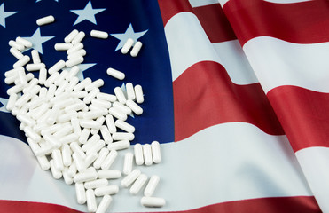 White pharmaceutical pills on to American flag