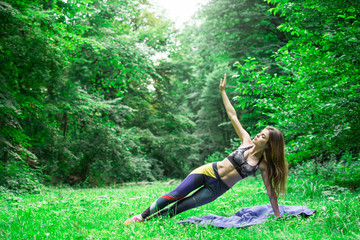 Yoga outdoor. Happy woman doing yoga exercises, meditate in the park. Yoga meditation in nature. Concept of healthy lifestyle and relaxation. Pretty woman practicing yoga on the grass