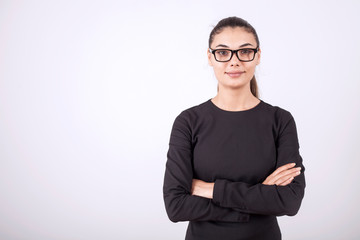 beautiful young businesswoman standing with crossed arms and smiling at camera in office