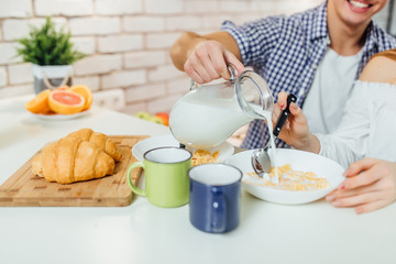 Close up photo of morning desk with cereal, milk,and croissant,healthy food. Man holding milk..