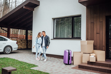 Full length rear view shot of young couple  near cardboard box at new home. Young man and woman with  boxes and moving in new house.