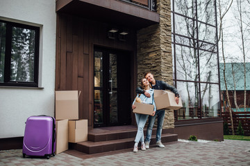 Two married person with unpacking boxes standing near luxury apartaments..