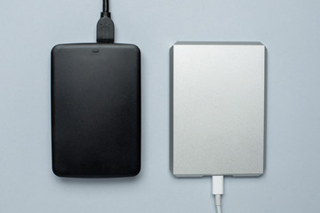 Black and silver removable hard drives on gray background.Minimal working desk.Storage and transfer...