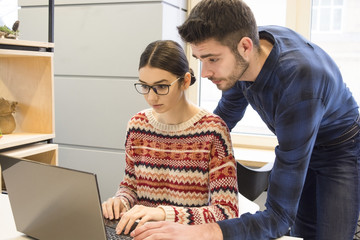 beautiful guy and girl are working on a laptop, students smiling