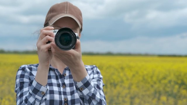 Female photographer in nature. Woman photographer on the field of blooming canola.