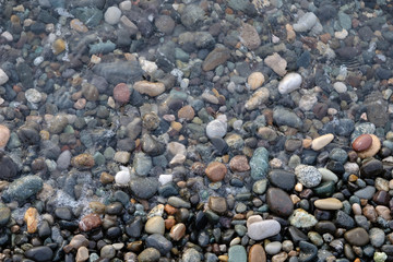 Abstract image of the water ripples over the stone pebbles in the Mediterranean Sea. Gray abstract background