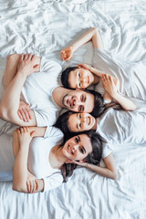 Top wiev. Young family lying on bed  with little kids  in apartment hotel.