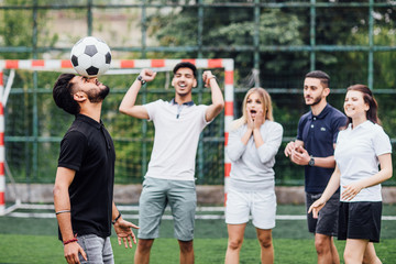 Fototapeta premium Soccer player man with dark skinned playing hitting head and his friends looking.