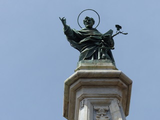 Fototapeta na wymiar Statua di bronzo di San Domenico all'estremità di un obelisco a Napoli in Italia.