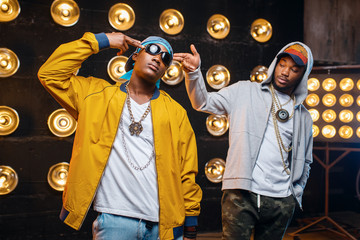 Two black rappers in caps, artists poses on stage