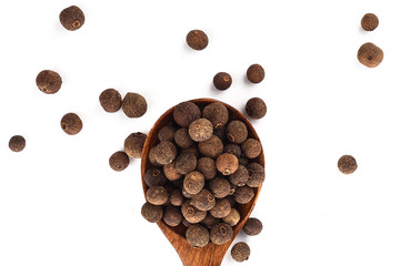 Pepper allspice on wooden spoon isolated on white background. Jamaican bell pepper. Close up