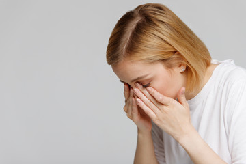 Young woman has a problem with contact lenses, rubbing her swollen eyes due to pollen, dust...