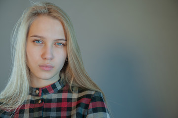 beautiful blonde with blue eyes in plaid dress touches her hair. Young actress shows acting exercises. woman actively expresses her emotions and poses for camera