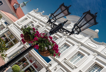 Street light in outlet Parndorf near Wien in Austria with nice flowers and building in light white color as the background with blue sky. The view under 45 degrees. 