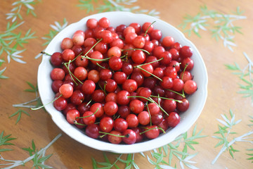 Sweet cherries in a white bowl on table. Cherry, first spring fruit