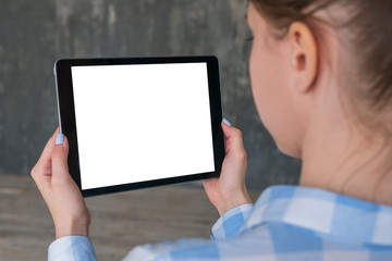 Over shoulder closeup view: woman hands holding digital tablet computer device with white blank screen in empty room. Mock up, copyspace, template, entertainment and technology concept