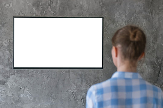 Mock up, copyspace, leisure time, template, entertainment and technology concept - woman watching flat smart led TV with white blank screen hanging on wall in the living room at home - mockup image 